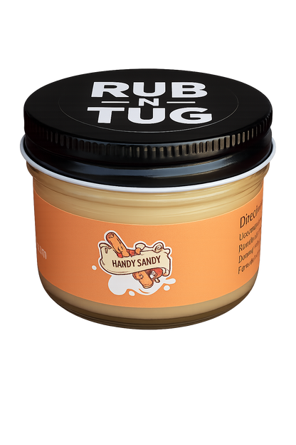 A close-up of the Rub N Tug "Handy Sandy" hair pomade jar, featuring a bold orange label with a playful cartoon log character gripping a banner that reads "Handy Sandy." The black lid prominently displays the Rub N Tug logo in white, and the glass jar rests against a smooth gradient background.  Handy Sandy by Rub N Tug — a premium, all-natural pomade with cheeky branding and long-lasting hold, developed by barbers for confident, playful styling.